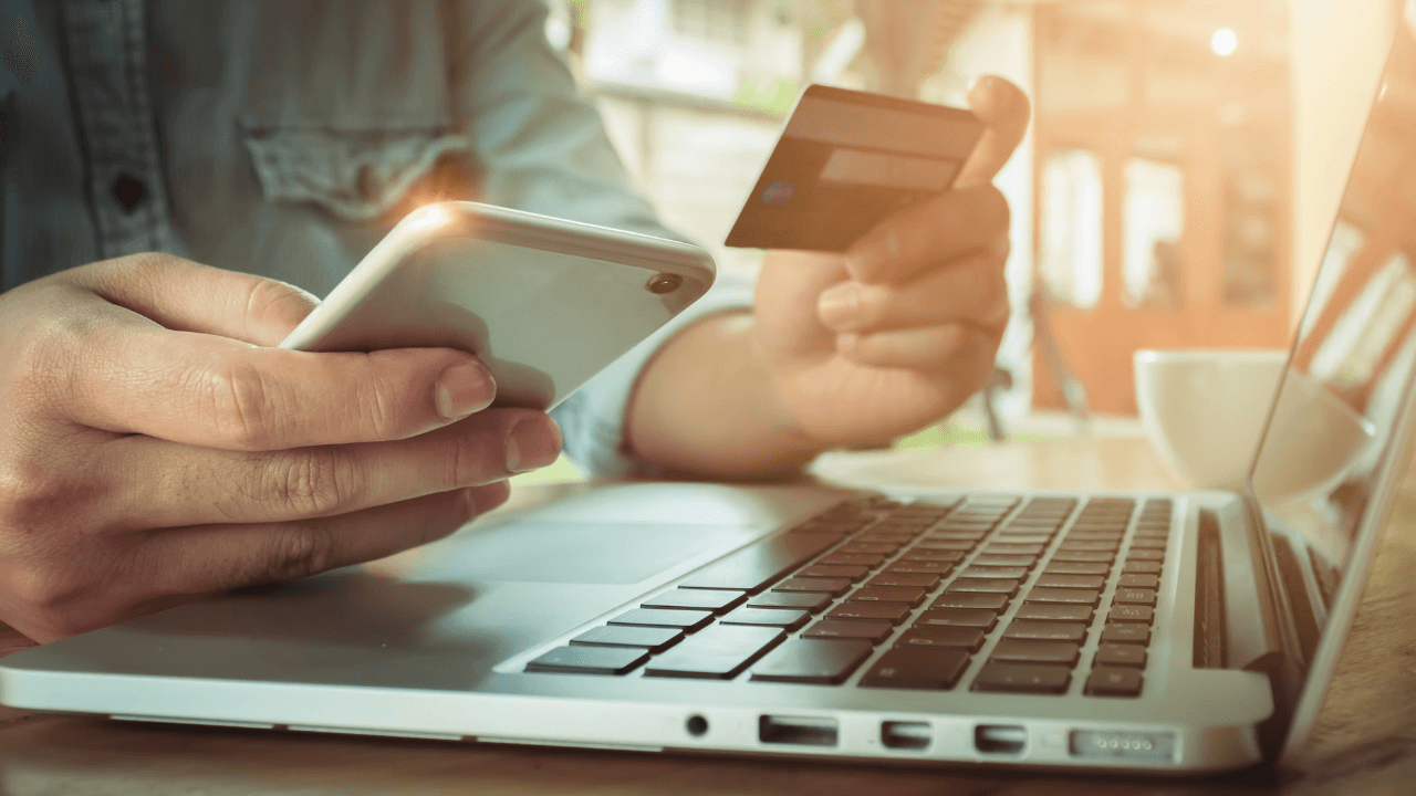 person using their phone and laptop to do a credit card transaction