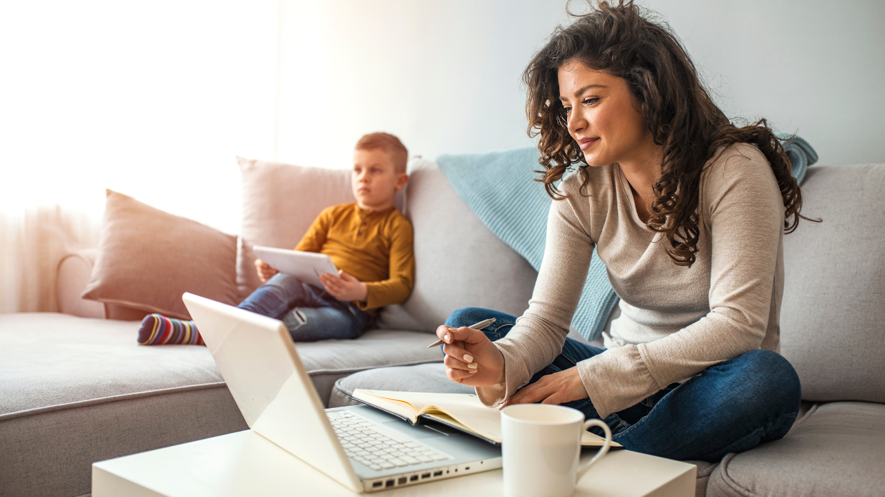 woman using a laptop while also holding a notebook